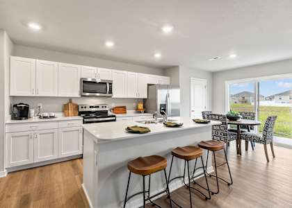 A kitchen with white cabinets and a large island with bar stools.
