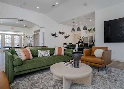 A living room with a green couch, a coffee table, and a large painting on the wall.
