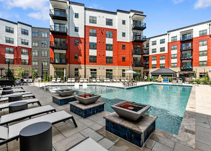 an outdoor pool with lounge chairs and fire pits at the bradley braddock road station at Tapestry West in Richmond, Virginia