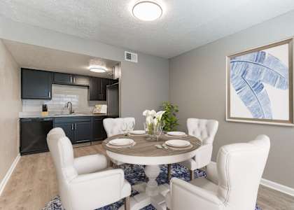 A dining room with a round table surrounded by white chairs at 46Eleven Apartments, Dallas, TX, 75228