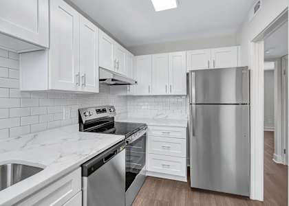 A kitchen with white cabinets and a stainless steel refrigerator.