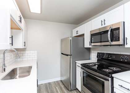 A kitchen with a stove, refrigerator, and microwave.