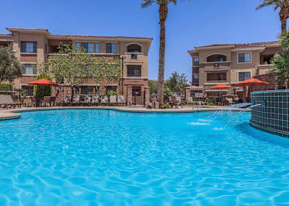 A large swimming pool in front of a building with palm trees.