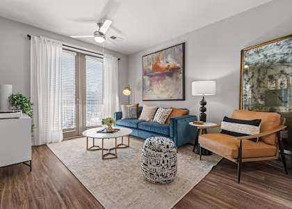 A living room with a blue couch, a patterned ottoman, and a painting on the wall. at 1010 Dilworth Apartments, Charlotte, North Carolina