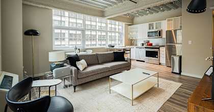 a living room with a couch and a coffee table    and a kitchen