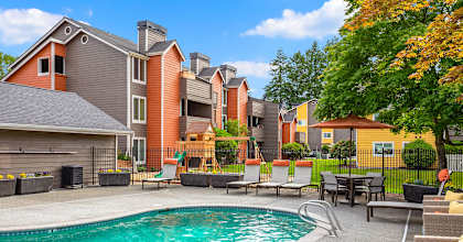 A swimming pool surrounded by chairs and buildings.