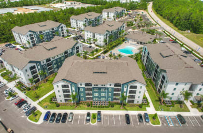 an aerial view of an apartment complex with a swimming pool and parking lot