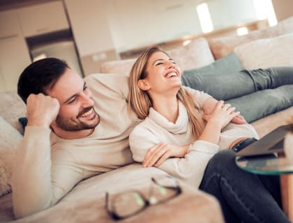 a couple laughing on a couch in a living room