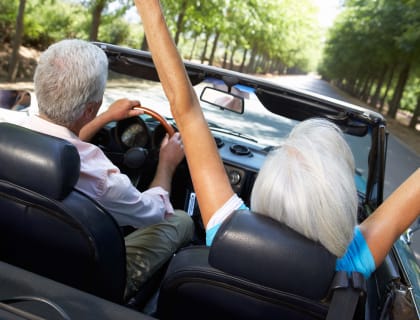 an older couple driving in a convertible car