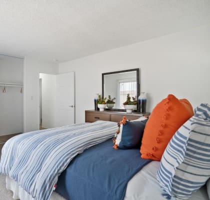 a bedroom with white walls and blue and orange pillows