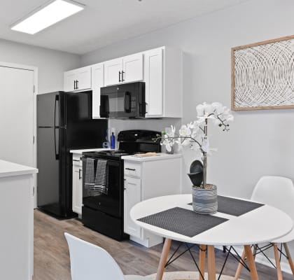 a kitchen and dining area with a white table and chairs and a black refrigerator