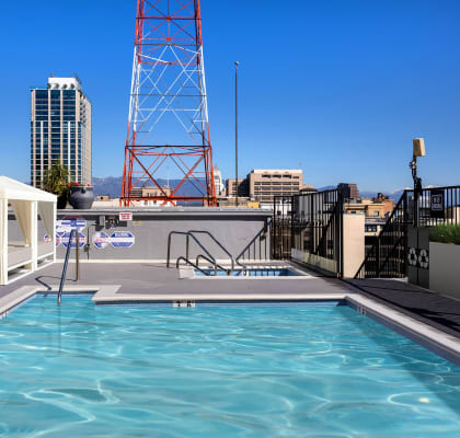 a rooftop pool with a white gazebo and a city in the background