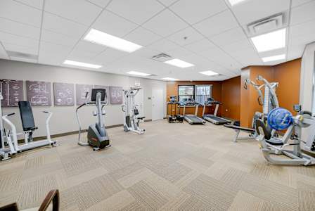A gym with a variety of equipment including treadmills, stationary bikes, and weight machines at Fullerton Court Apartments, Chicago, 60614