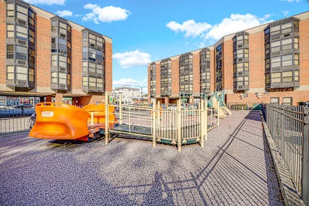 A playground area in front of a building with orange and grey buildings in the background at Fullerton Court Apartments, Chicago, Illinois