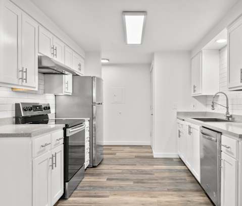 A modern kitchen with white cabinets and stainless steel appliances.