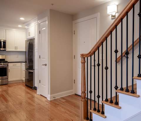 a staircase in a home with wood floors and a black railing at Zephyr Ridge Apartment Homes, Cedar Grove, New Jersey