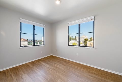 a bedroom with two windows and a hardwood floor at K Street Flats, Berkeley