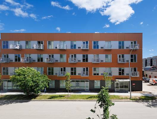 A large building with orange and white panels and balconies.