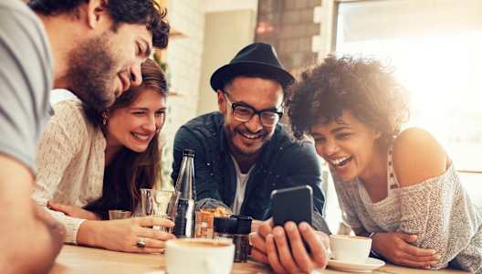 a group of people sitting at a table looking at a cell phone