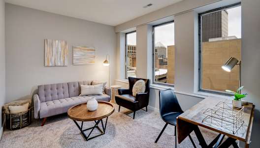 A living room with a grey couch, a coffee table, a chair, and a table with a plant on it.
