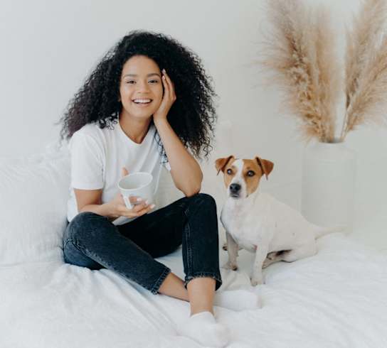 Woman Smiling while Sitting on Bed with Dog at Koi Apartments, Seattle, Washington