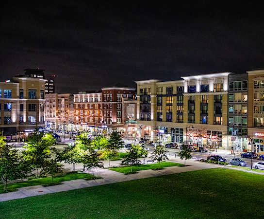 a city at night with cars parked on the side of the road at The Met at Metro Centre Apartments, Owings Mills, MD 21117