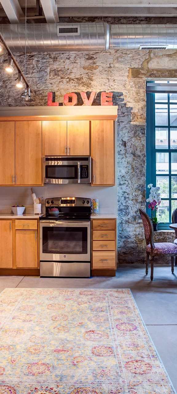a kitchen with wooden cabinets and stainless steel appliances in a loft