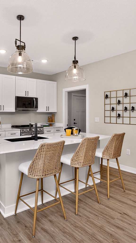 A kitchen with a white island and chairs.