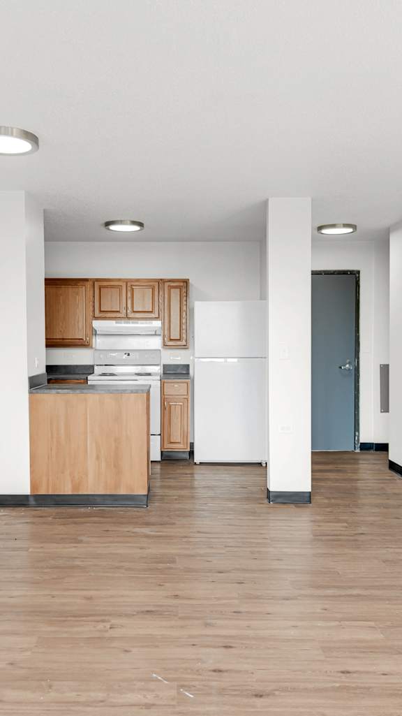A long, empty hallway with a kitchen area at the end at Fullerton Court Apartments, Illinois
