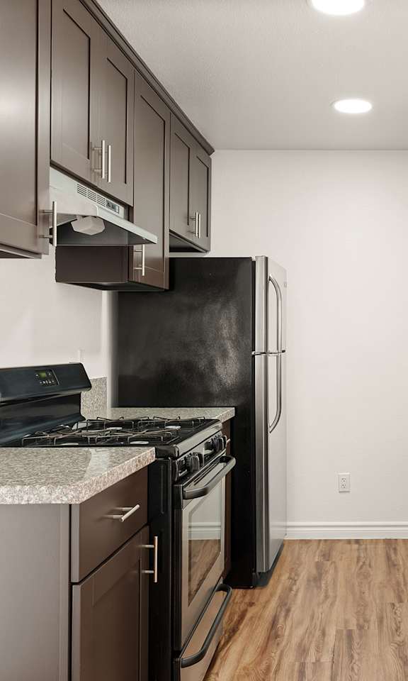 A kitchen with brown cabinets and a black fridge.