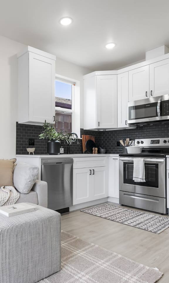 a living room with a couch and a kitchen with stainless steel appliances