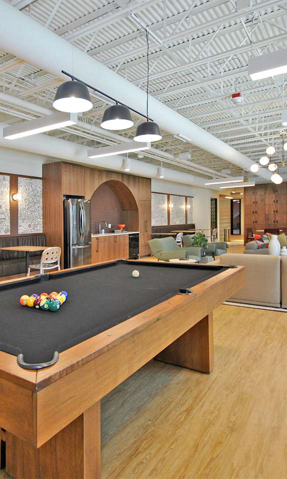 A pool table is in the middle of a room with a couch and chairs.