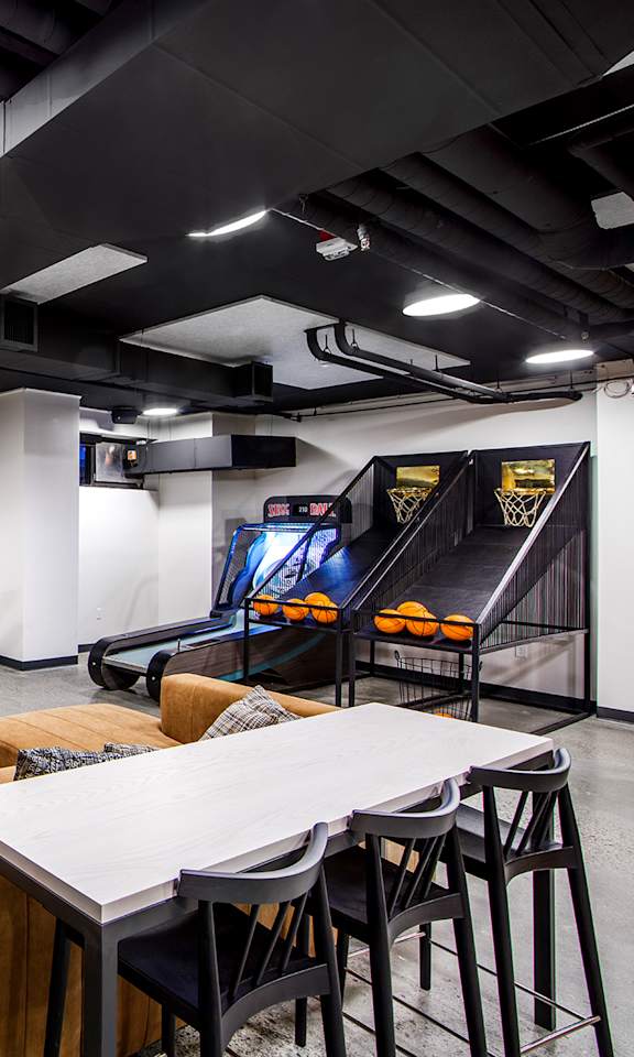 A modern office space with a yellow and green wall mural, a white table, and a black bean bag.