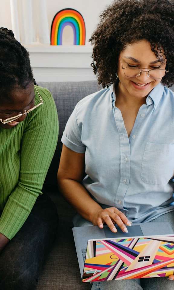 Women Sitting on Couch Looking at Laptop Together