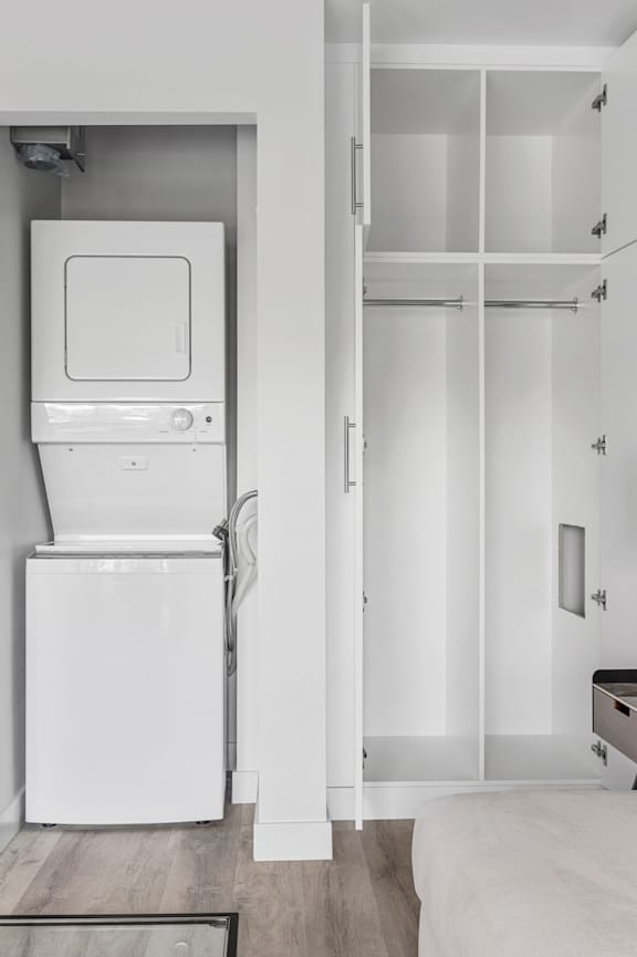 A white kitchen with a refrigerator, oven, and a white couch.