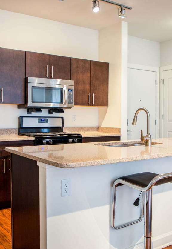 a kitchen with an island and two stools at Metro Crossing Apartments, Owings Mills, Maryland