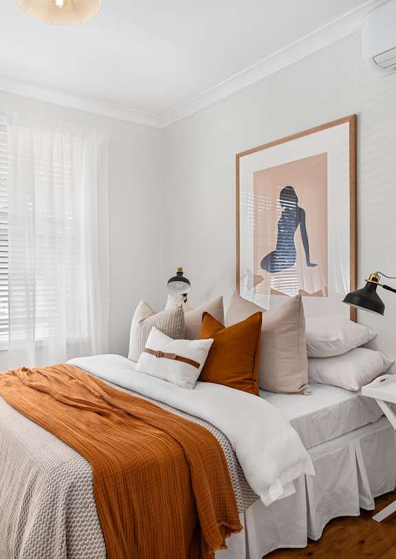 A bedroom with a bed, a nightstand, and a painting on the wall.