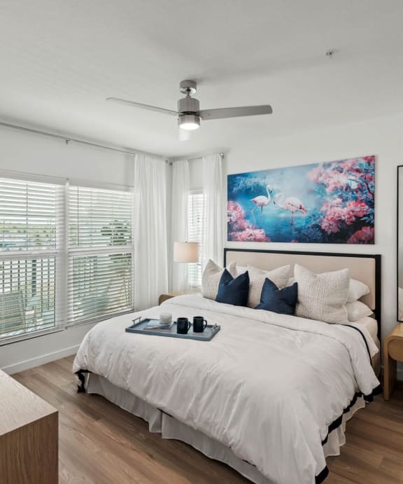 A bedroom with a large bed, a ceiling fan, and a painting on the wall. at Altis Twin Lakes Apartments, Kissimmee, FL 34744