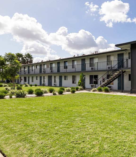 A row of white houses with a concrete pathway in the middle.