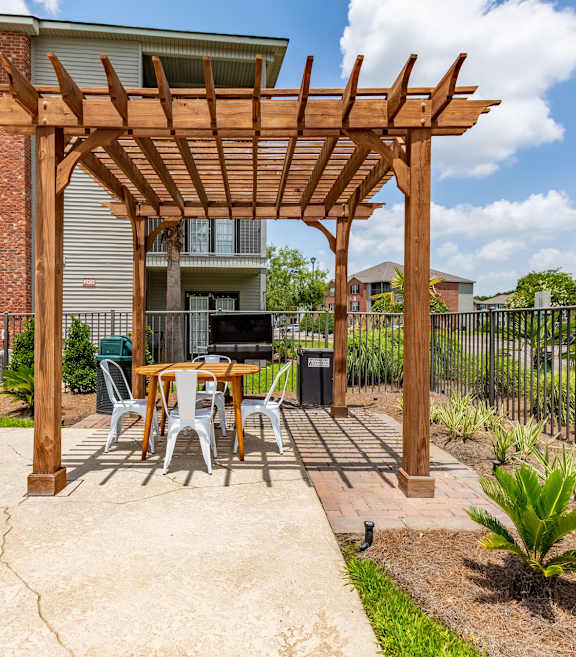 A wooden pergola is over a table set for four.