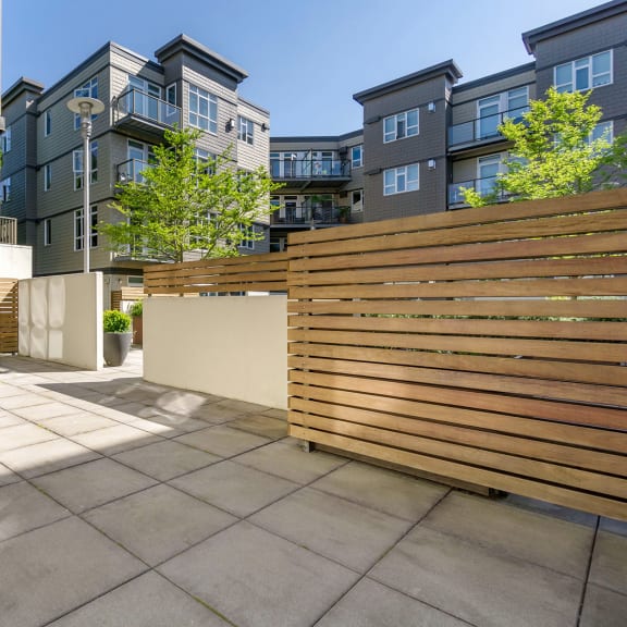 a private patio with a wood slatted privacy fence in front of an apartment building at 128 on State, Kirkland, 98033