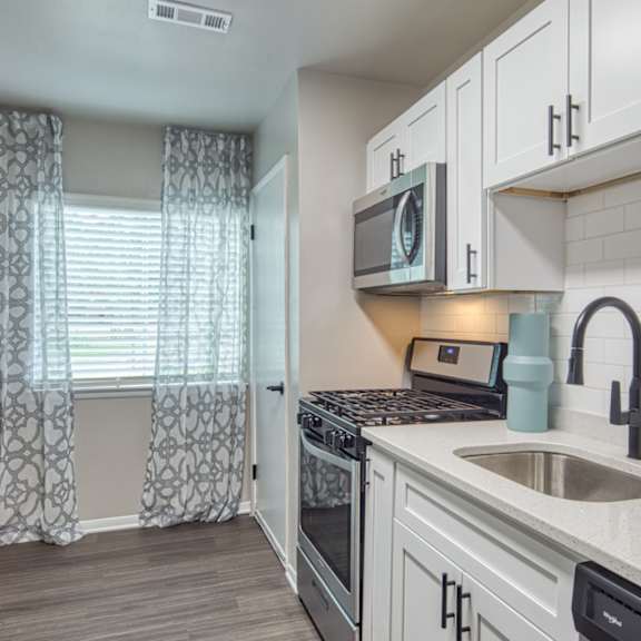 A kitchen with a sink, stove, and cabinets.