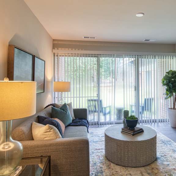 A living room with a grey couch, a yellow chair, a round table, and a television.