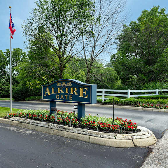 The entrance to the Alkire Gate community with a sign and flags.