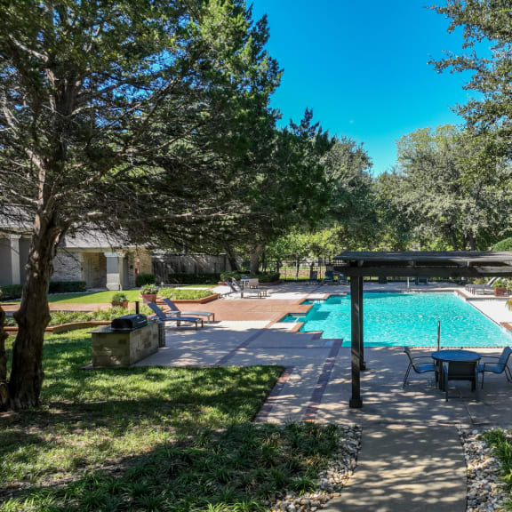 a resort-inspired swimming pool surrounded by lush landscaping at Stoneleigh on Spring Creek apartments