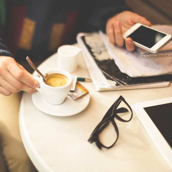 hand holding a white coffee cup on a white table
