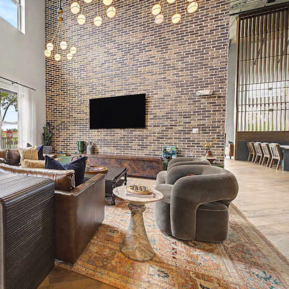 A living room with a brick wall and a flat screen TV.
