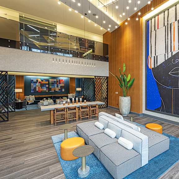 A large blue and black painting hangs on a wall above a grey couch in a modern room.