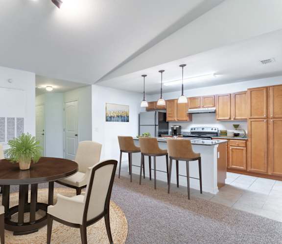 a dining area with a table and chairs and a kitchen in the background