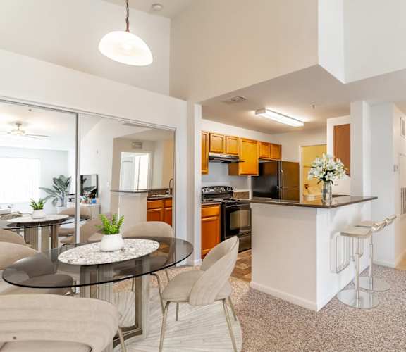 a living room with a table and chairs and a kitchen in the background